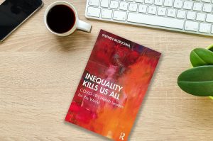 Book titled Inequality Kills Us All on a desk with a cup of coffee and computer keyboard