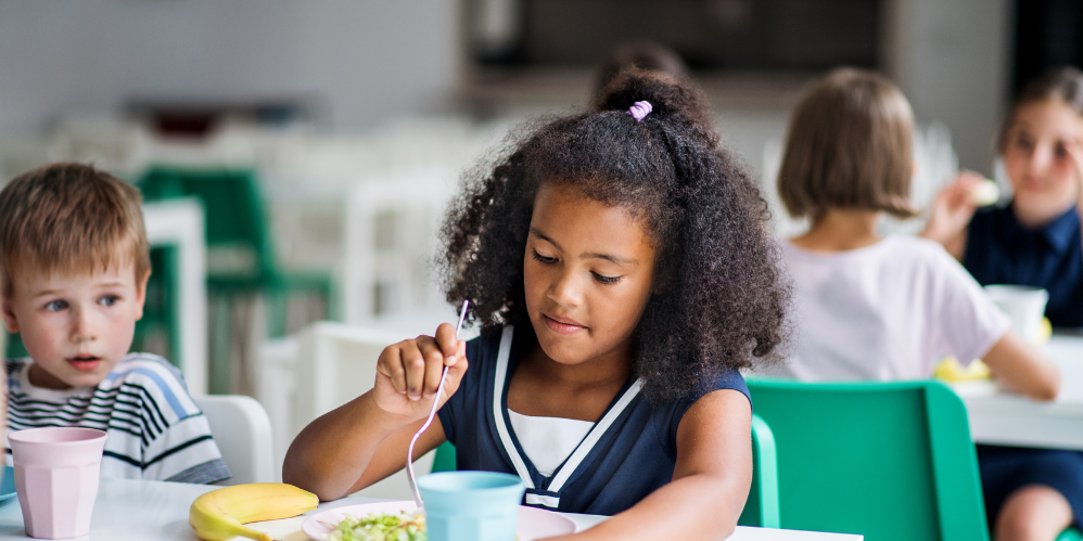 Young girl eats lunch in cafeteria