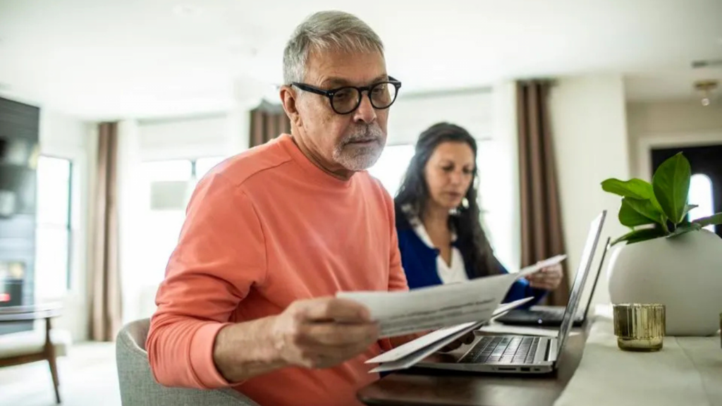 Older adult sorts through bills at a desk with 