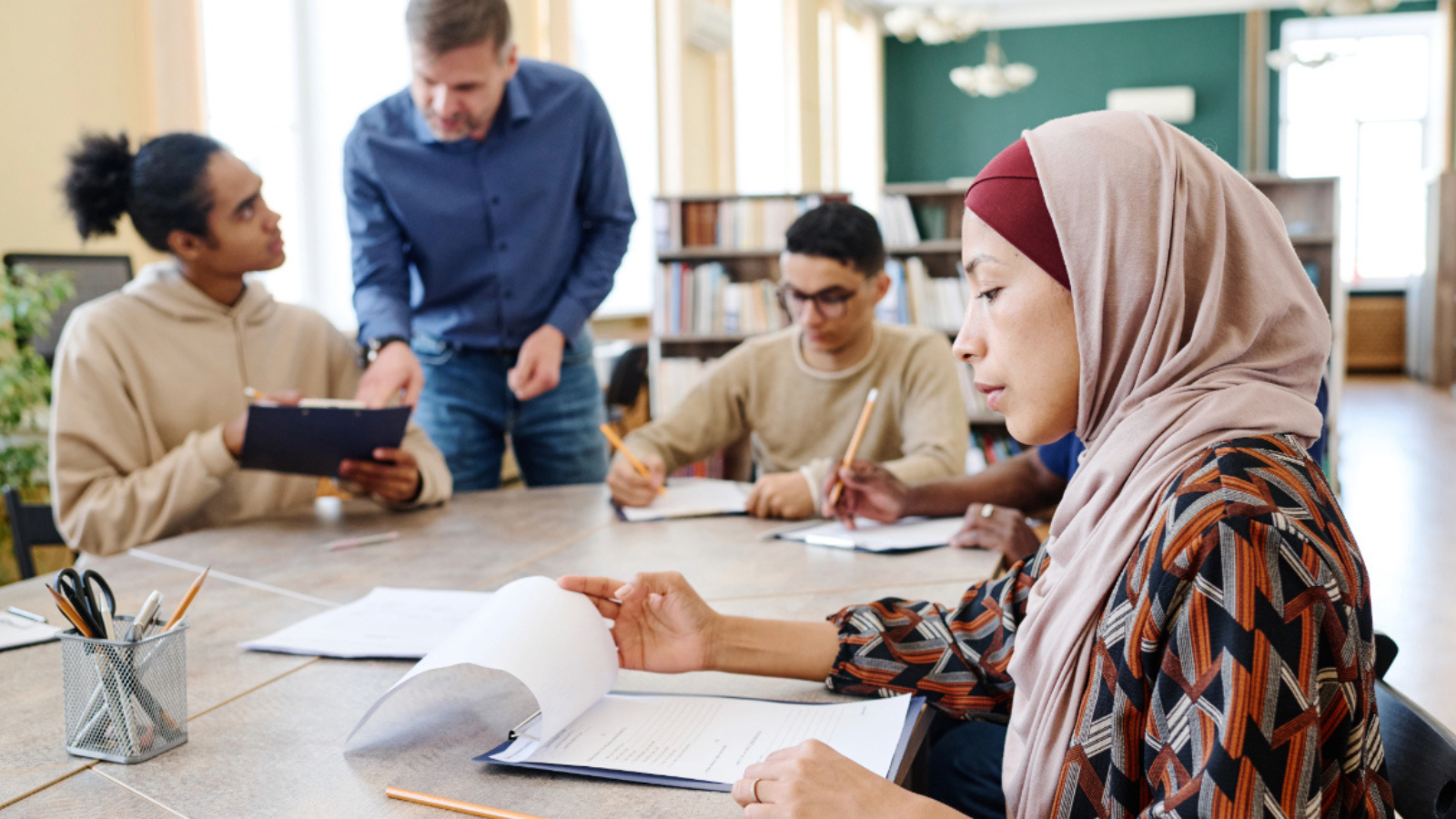 Hijabi woman looks over notes in team meeting for work.