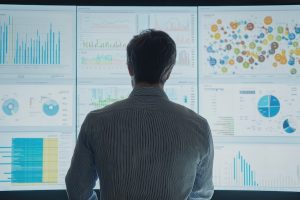 man examining data visualizations on a large video screen