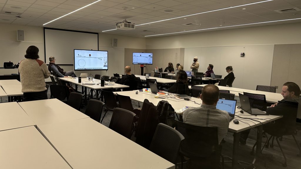 Executive M-H-A students interact simultaneously with colleagues in the classroom and an individual on an internet feed.